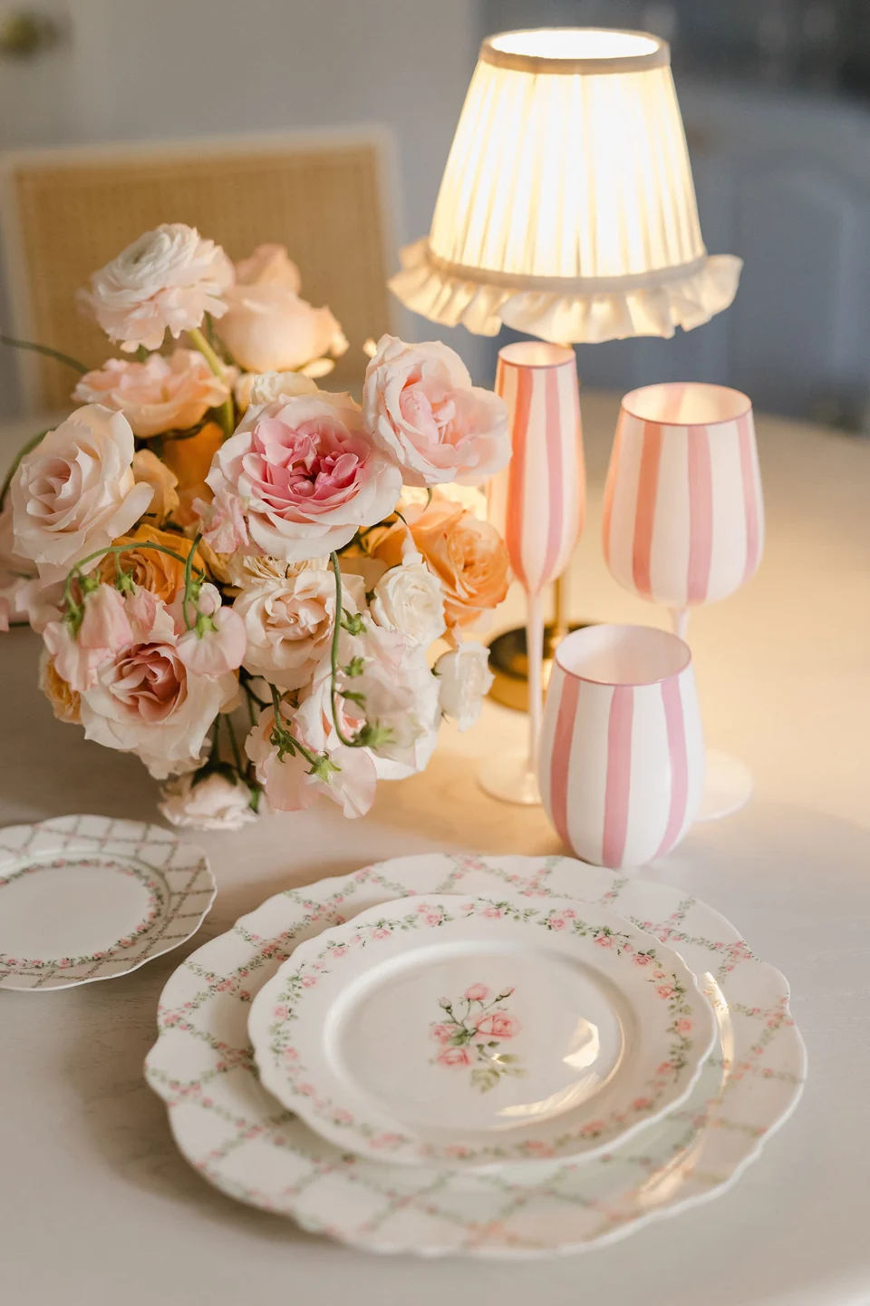 Rosette floral plates styled with pink striped glasses, roses and a small table lamp
