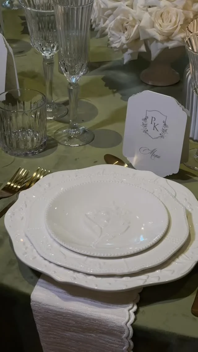White Lily of the Valley plates layered with clear stemware and gold cutlery