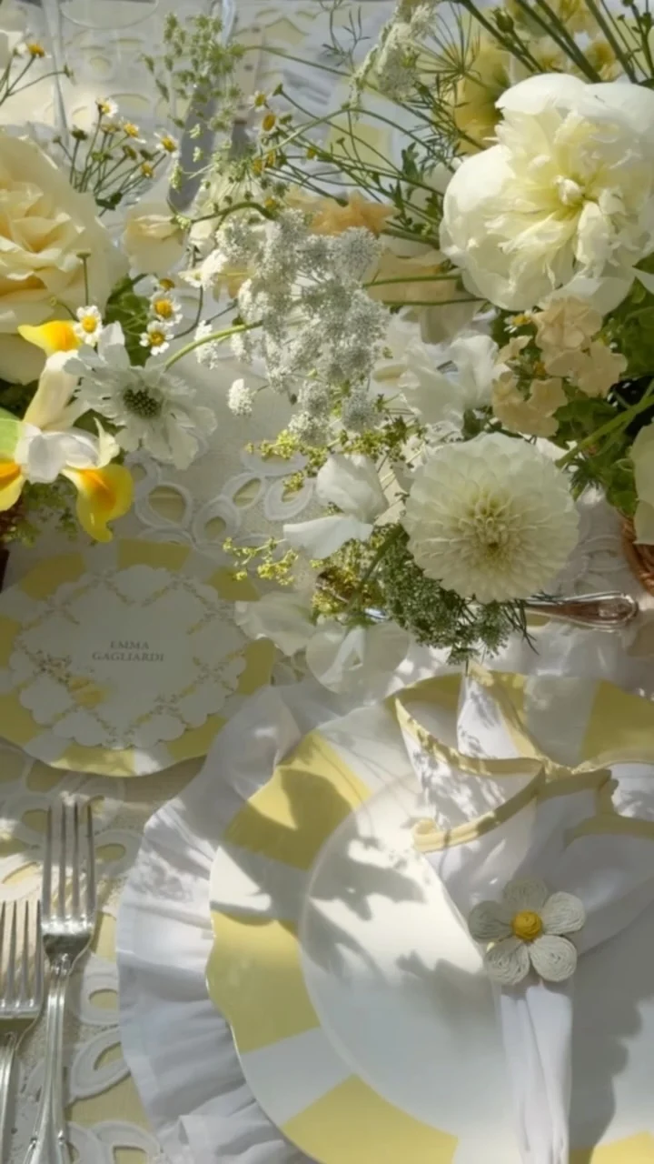 Yellow and white striped plates, a scalloped napkin and white flowers at a bridal shower table
